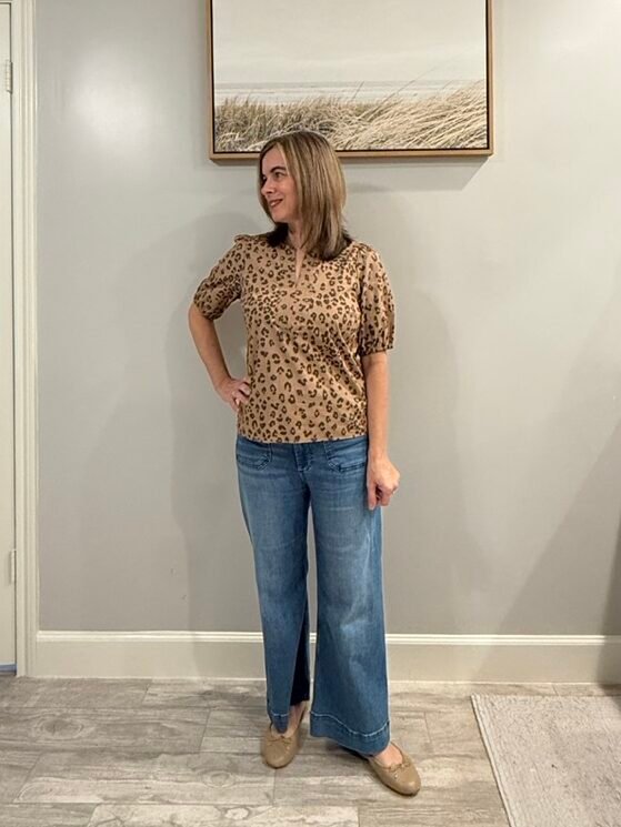 Women wearing loose fit leopard top with puff sleeves, wide leg jeans and ballet flat shoes.