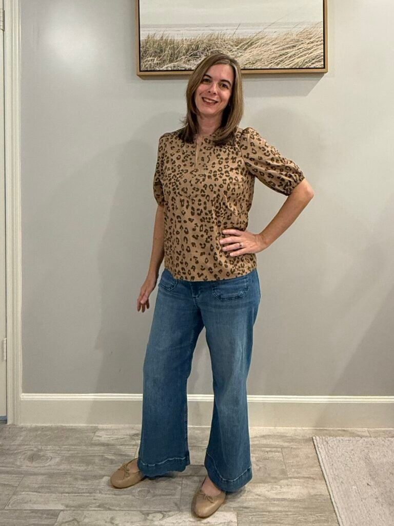 Women wearing leopard outfit with puff sleeve leopard top, wide leg jeans and ballet flat shoes.