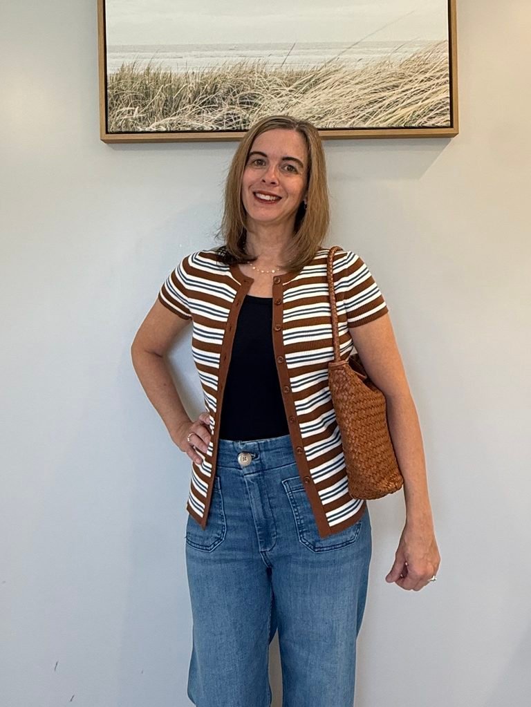 Women wearing open front cardigan with jeans and brown woven shoulder handbag.