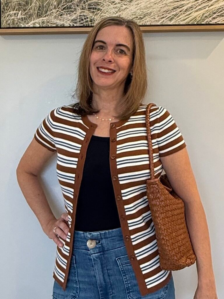 Women wearing open front cardigan with brown woven handbag.