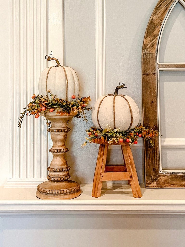Cream and orange pumpkins on wooden candlesticks with fall berry candlestick wreaths