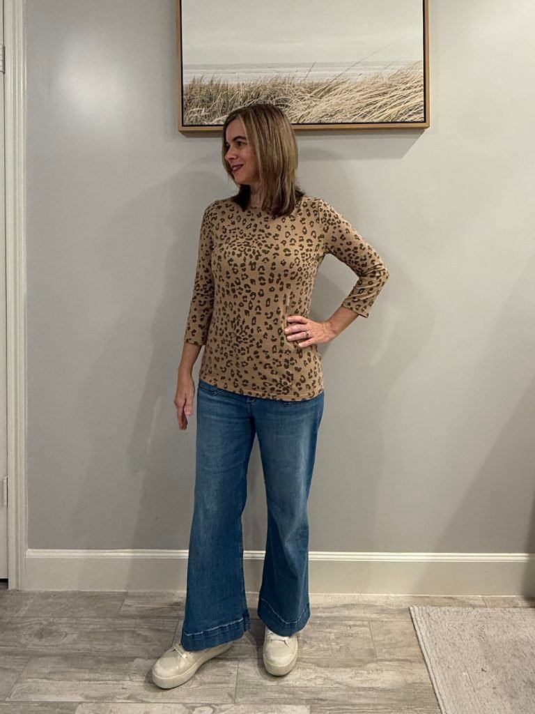 Women wearing 3/4 sleeve leopard top, wide leg jeans and sneakers.