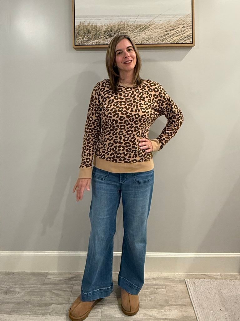 Women wearing leopard sweater, wide leg jeans and Uggs.