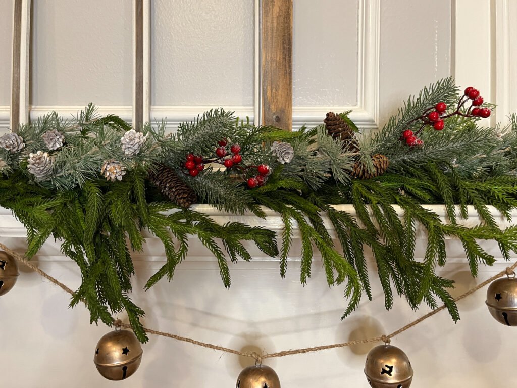 frosted greenery and pinecone picks layered into a mantel garland