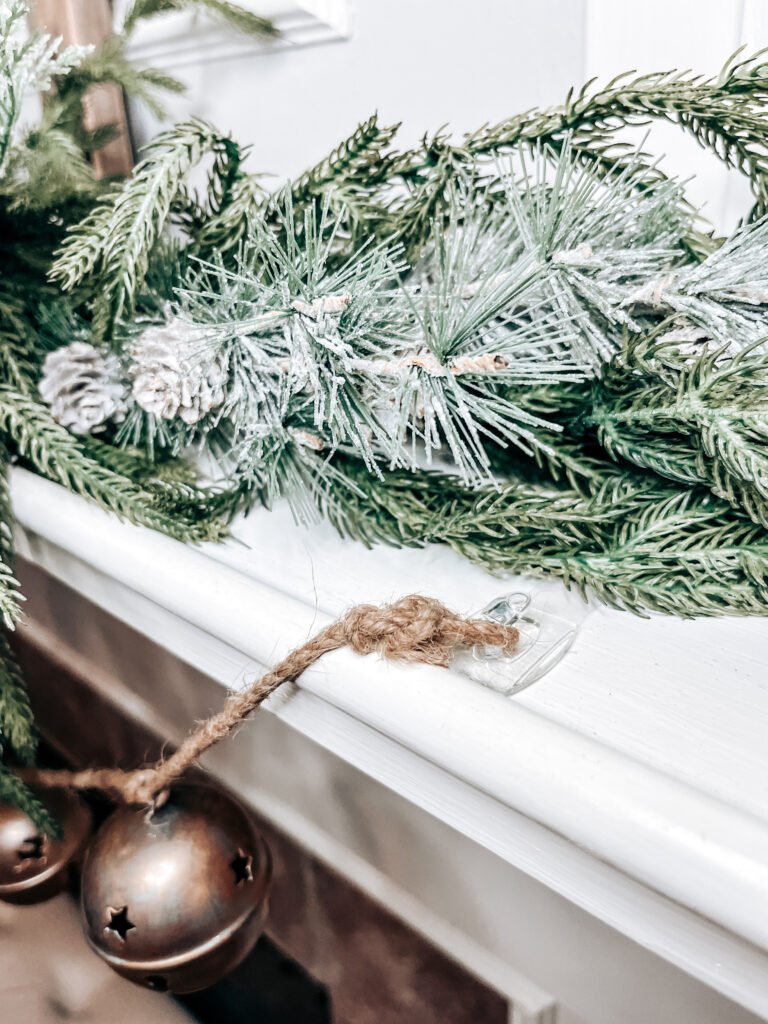 Gold bell garland attached to fireplace mantel with command hooks.